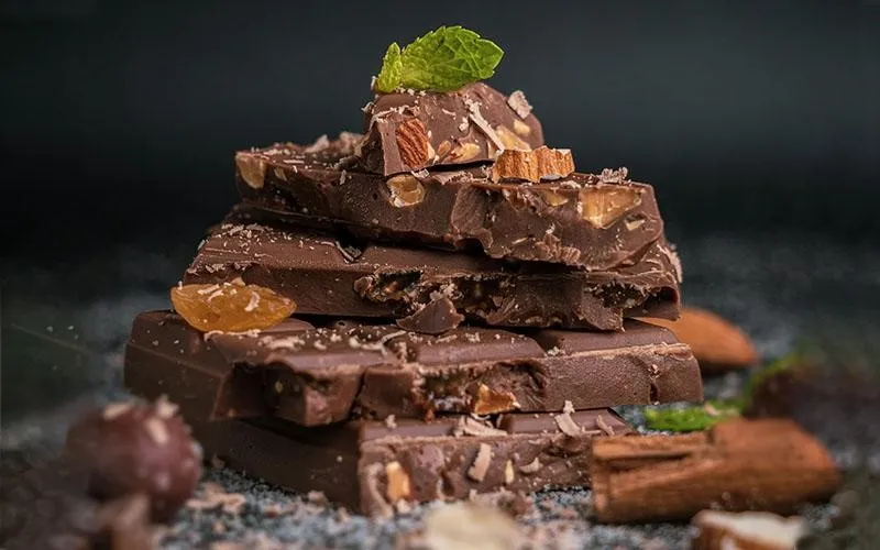 عکسی کلوزآپ از سطح شکلات بافت‌دار که با زاویه ماکرو گرفته شده و جزئیات ریز و واقعی آن را به‌وضوح نمایش می‌دهد؛ ایجاد حس کیفیت و تحریک حس چشایی مخاطب